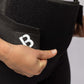A woman's hand pulling the black BioMagnetic Back Support belt closed at the front. 
