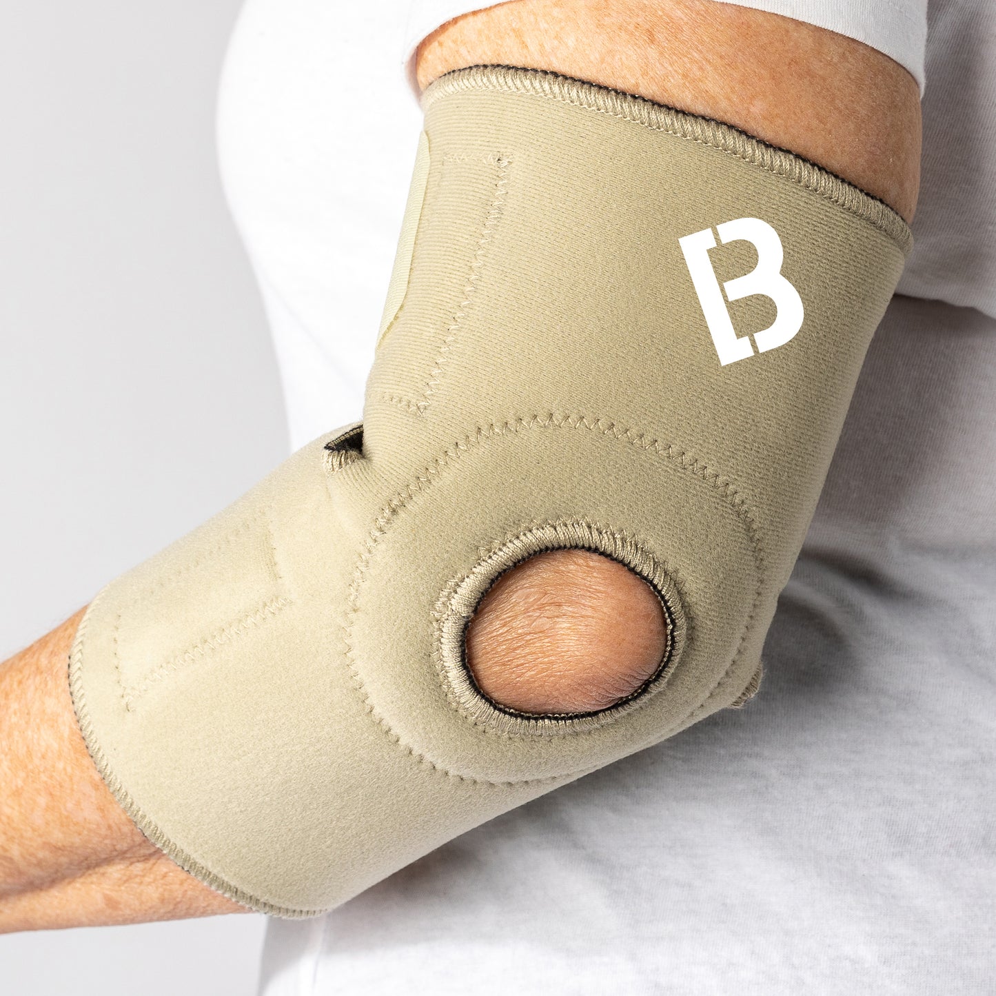 Beige Bio Magnetic Elbow Support on Elderly Woman, elbow slightly bent and view from the back
