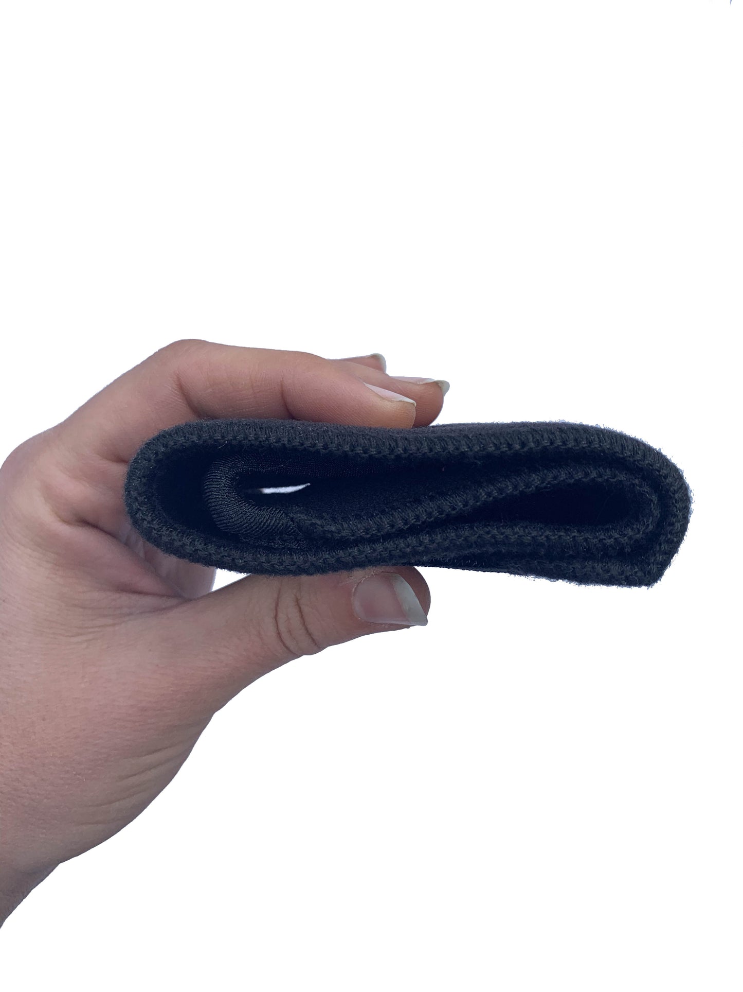 A hand holding the black bio magnetic wrist support folded up, showing how compact it is. 
