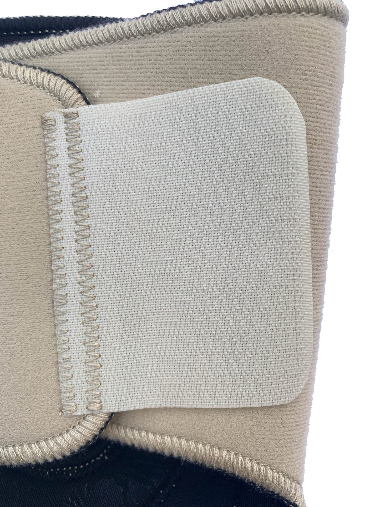 The Bio Magnetic Knee Support in beige up close showing the back of the upper adhesive tab that holds the support in place. 