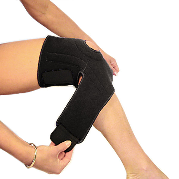 A woman putting on the bio magnetic knee support in the second step. She is fastening the straps around her upper calf, just below her knee. The magnetic knee support featured is in black.