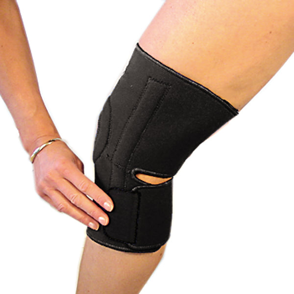 The last step in fastening the bio magnetic knee support in black. The bottom strap is being secured into place just below the knee cap on the left side.