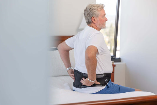 Man Sitting on bed wearing BioMagnetic Large XLarge Back Support.