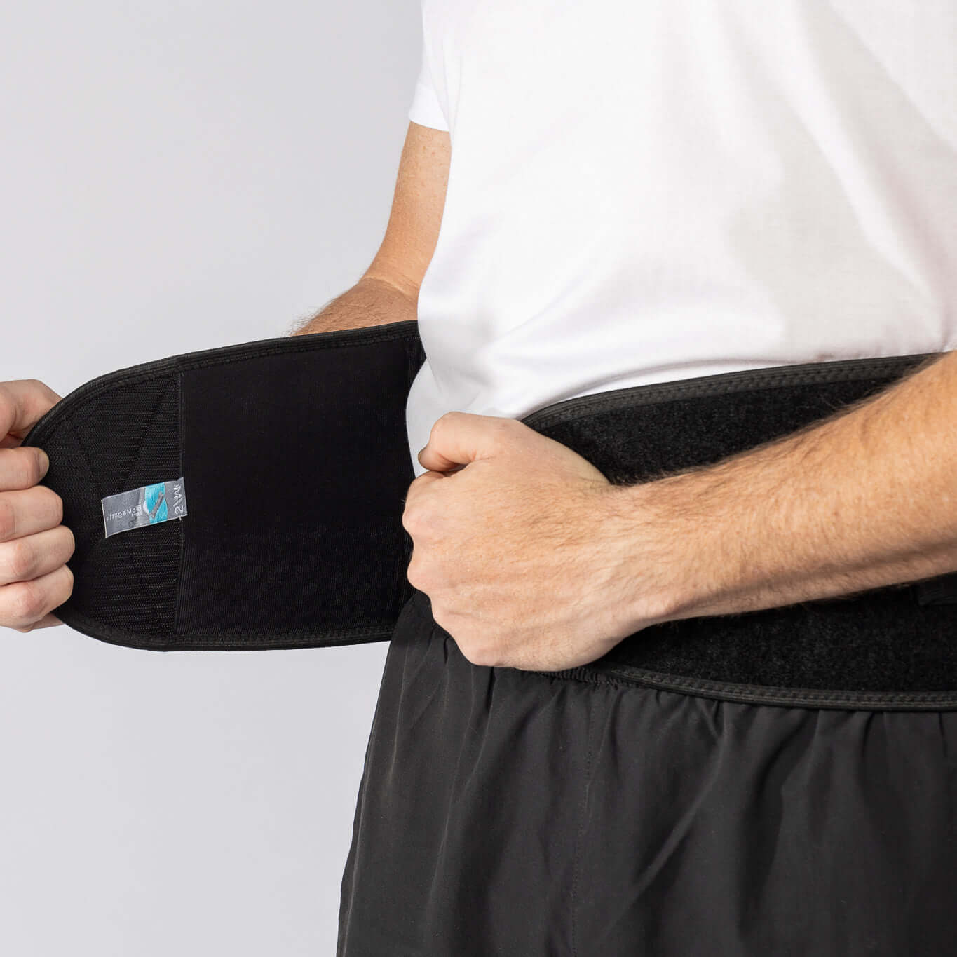 A Man putting on the Bio magnetic Back Support Belt, showing how the front closure folds over for optimal support.