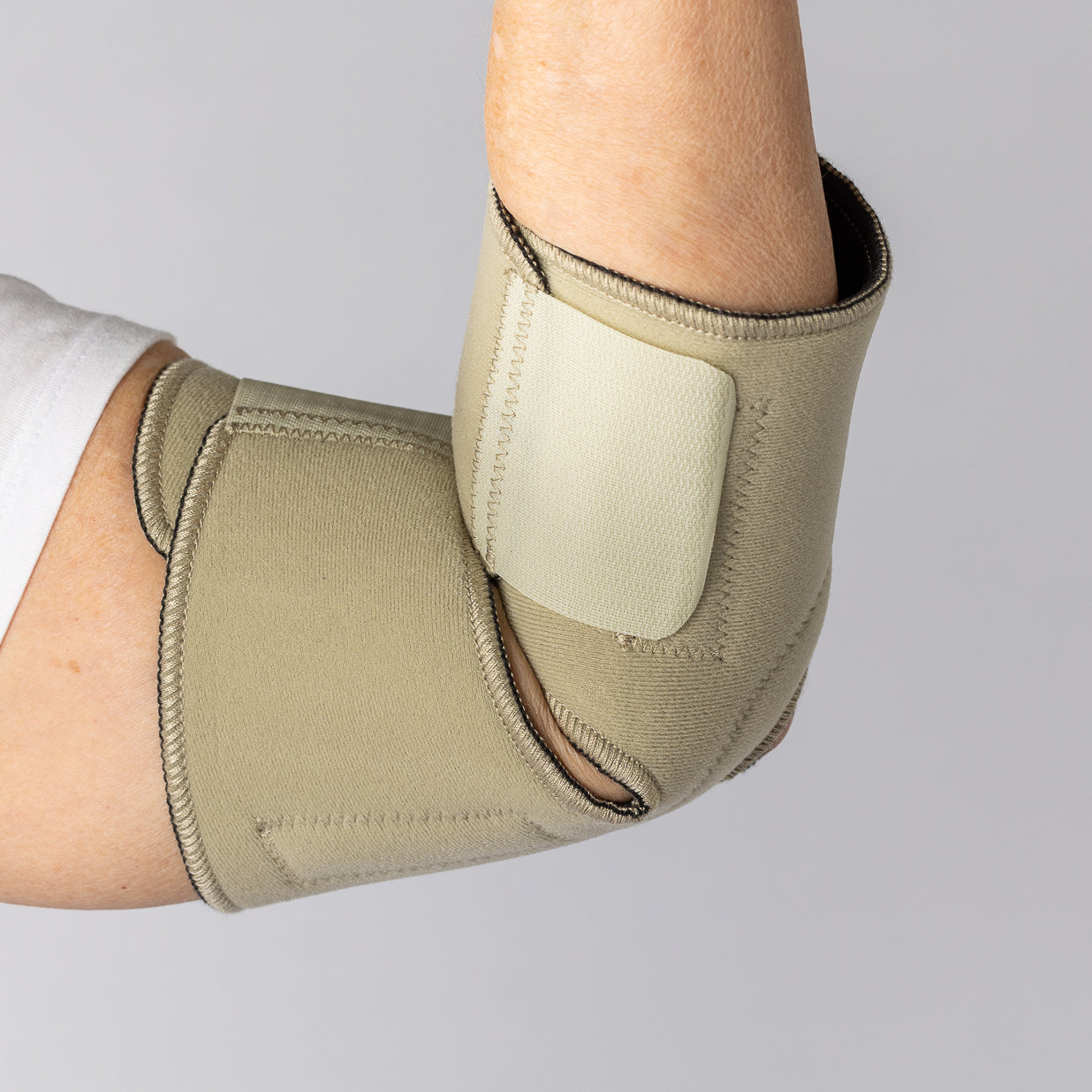 Bio Magnetic Elbow Support in Beige from the front inside view on an elderly woman.