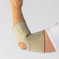 Bio Magnetic Beige Elbow Support Brace from the back view on a woman with her elbow bent and held up.