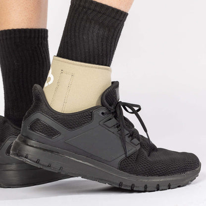 The BioMagnetic Ankle Support in beige being worn by a man wearing a black shoe, showcasing how the magnetic ankle support can be worn with most footwear. The view is from the side angle of the right foot. 