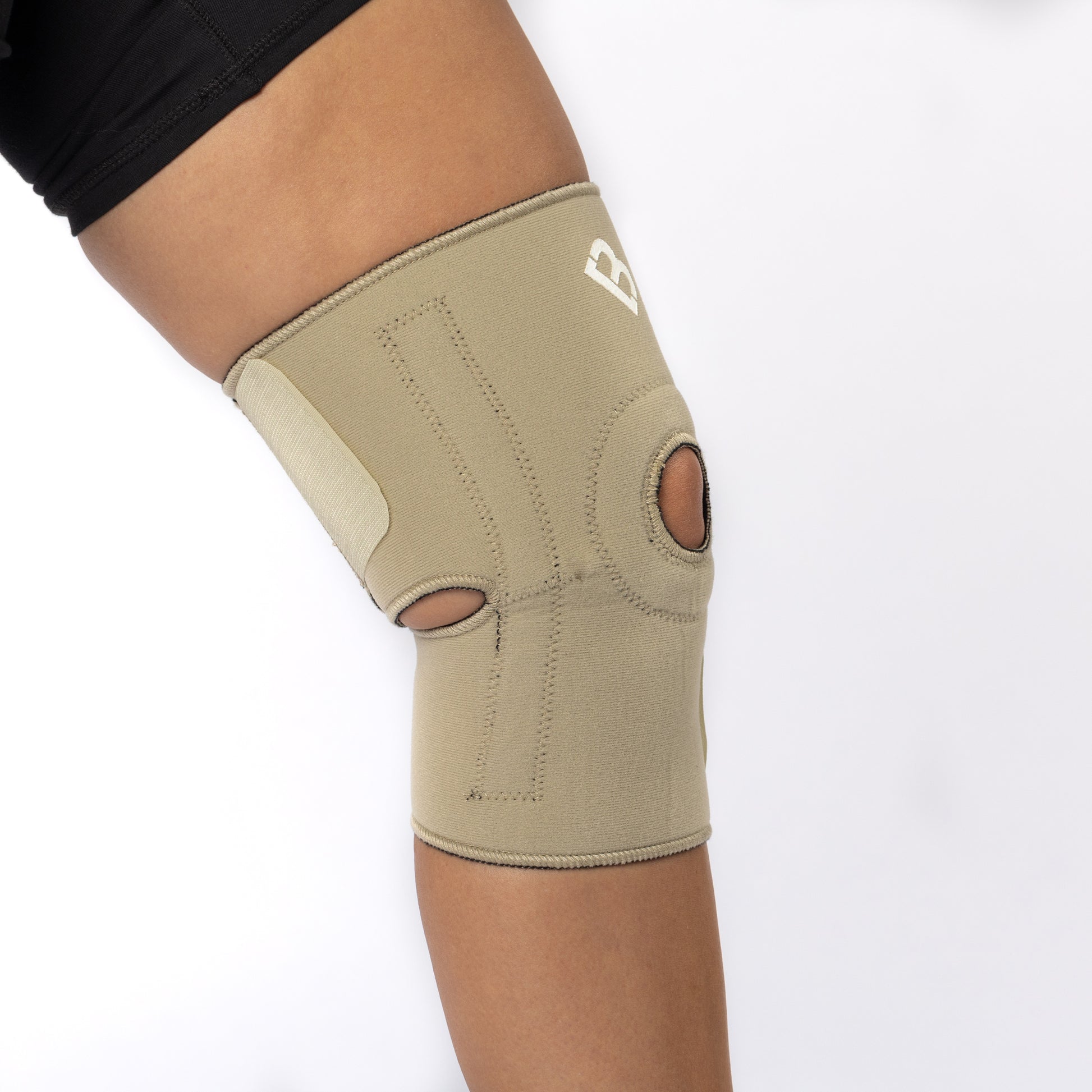 The Bio Magnetic Knee Support in beige being worn by a woman and it is viewed from the side, showing how the back straps attach around the leg for a secure fit.