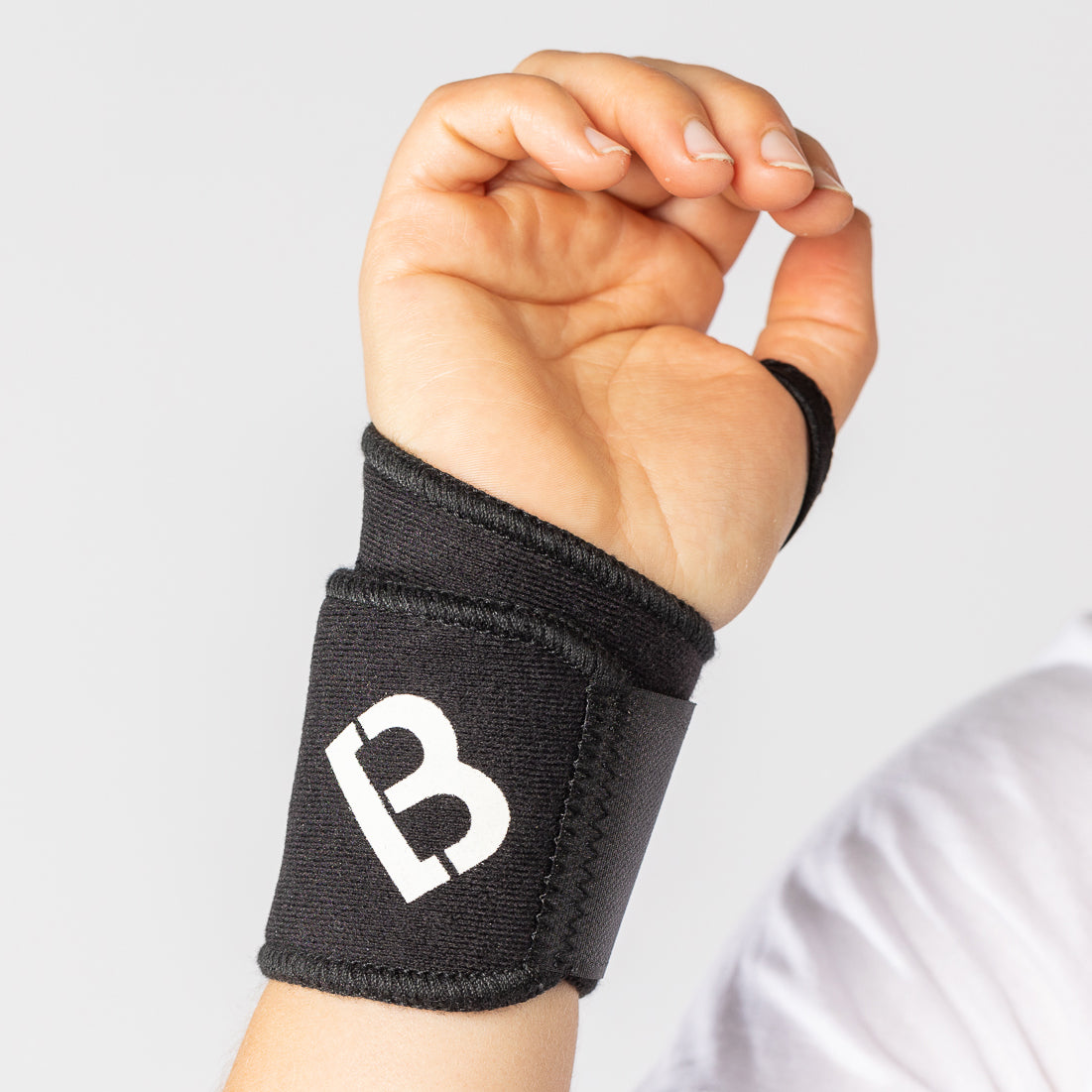 Woman wearing the black Bio Magnetic Wrist Support made of neoprene material on her right hand with the palm facing forward. 