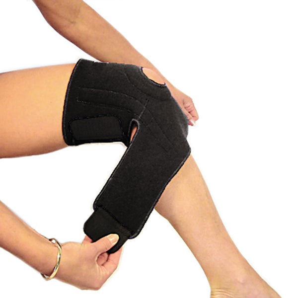 A woman putting on the bio magnetic knee support in the second step. She is fastening the straps around her upper calf, just below her knee. The magnetic knee support featured is in black. 