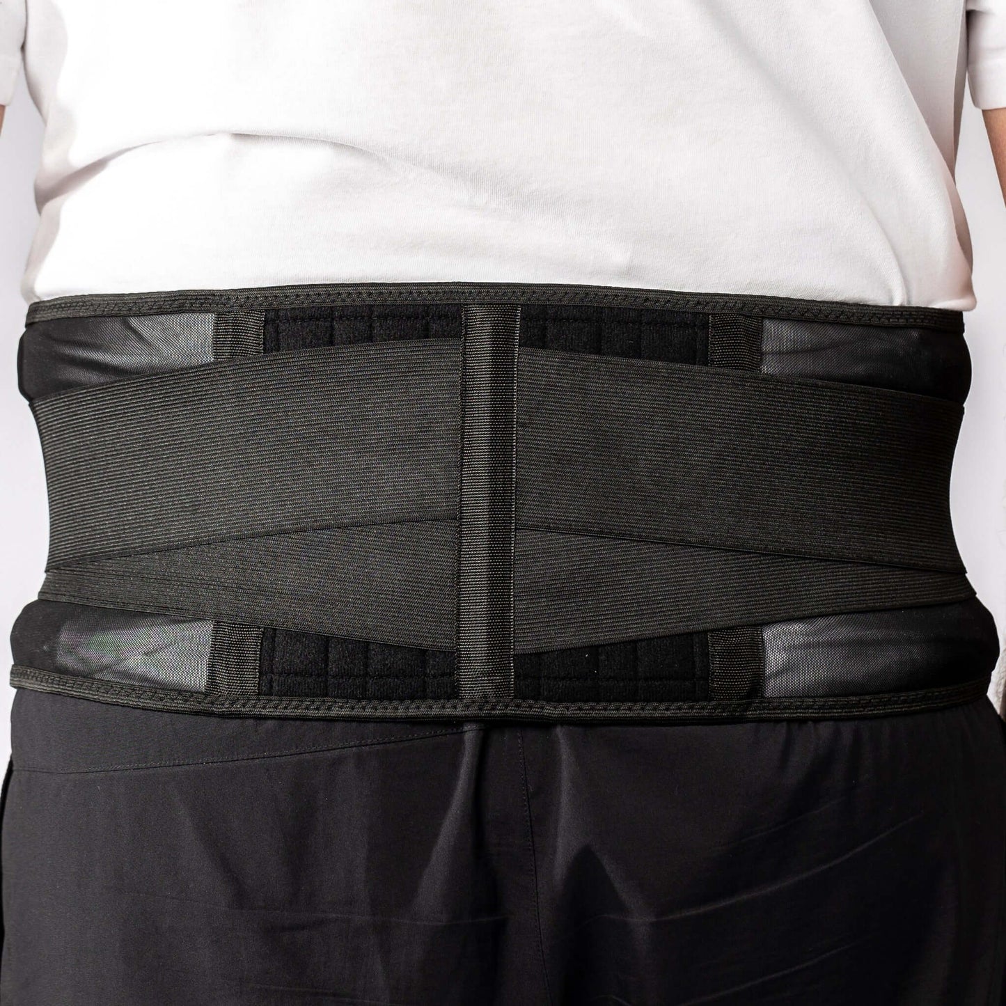 Middle aged man wearing a black biomagnetic Back Support with triple adhesive closure, vented sides and supportive back with 20 therapeutic magnets.